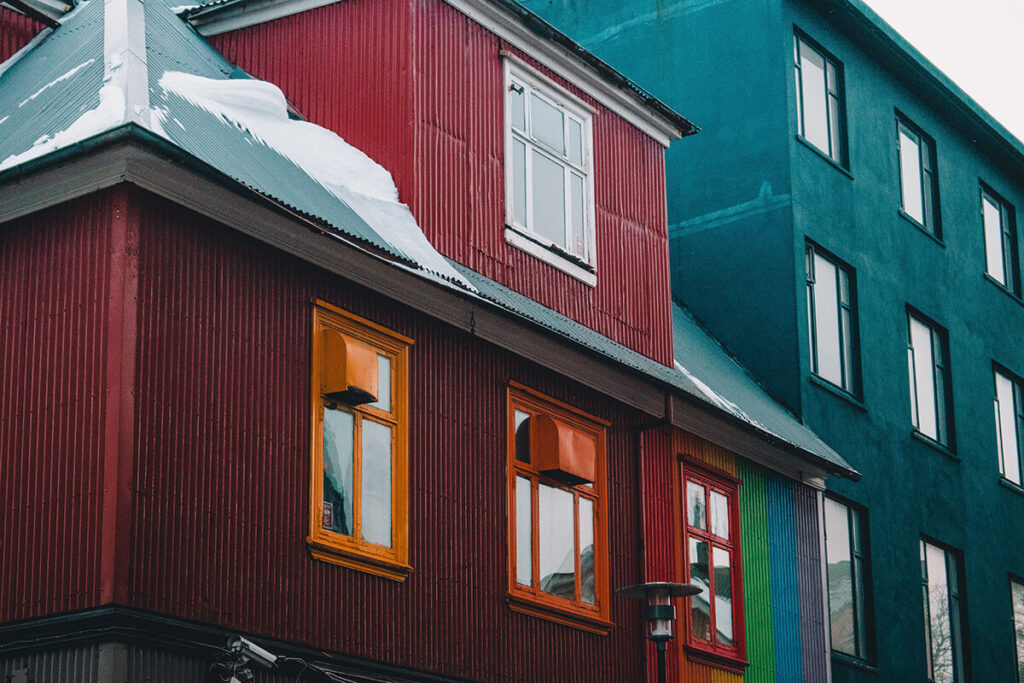 Red and green house side by side on snowy day