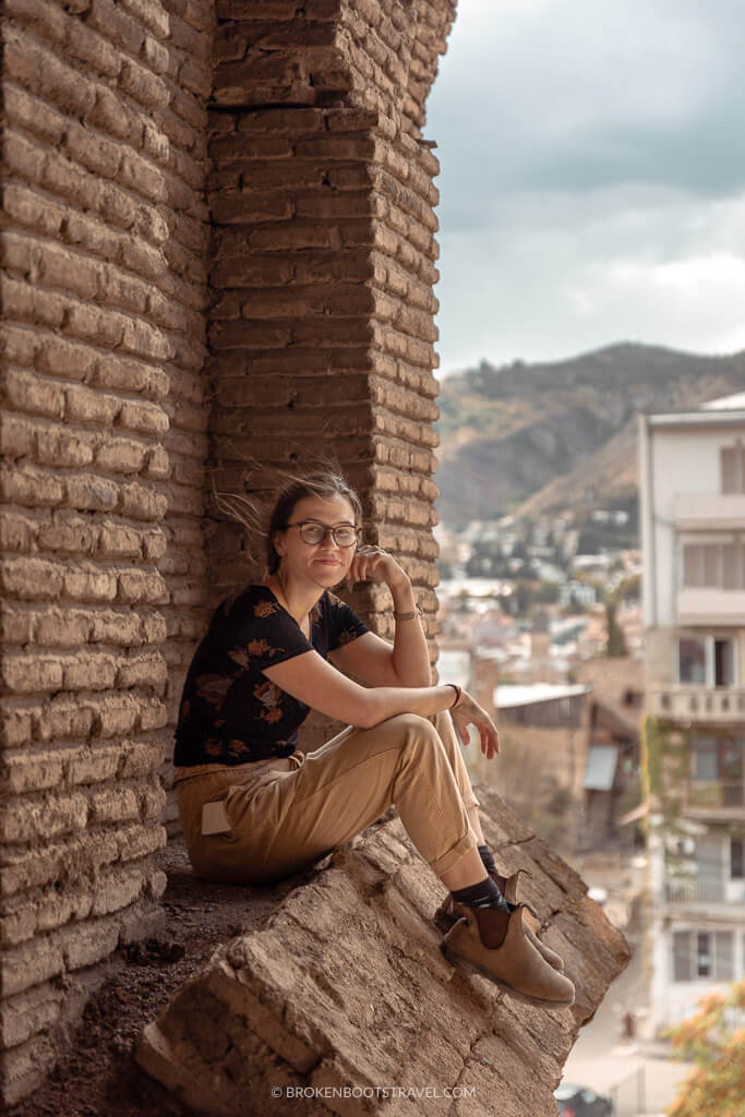 Girl smiling at the camera on a ledge above a city skyline