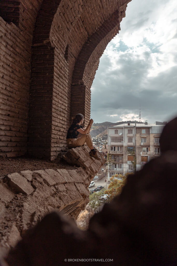 Girl sitting on a ledge above a city skyline