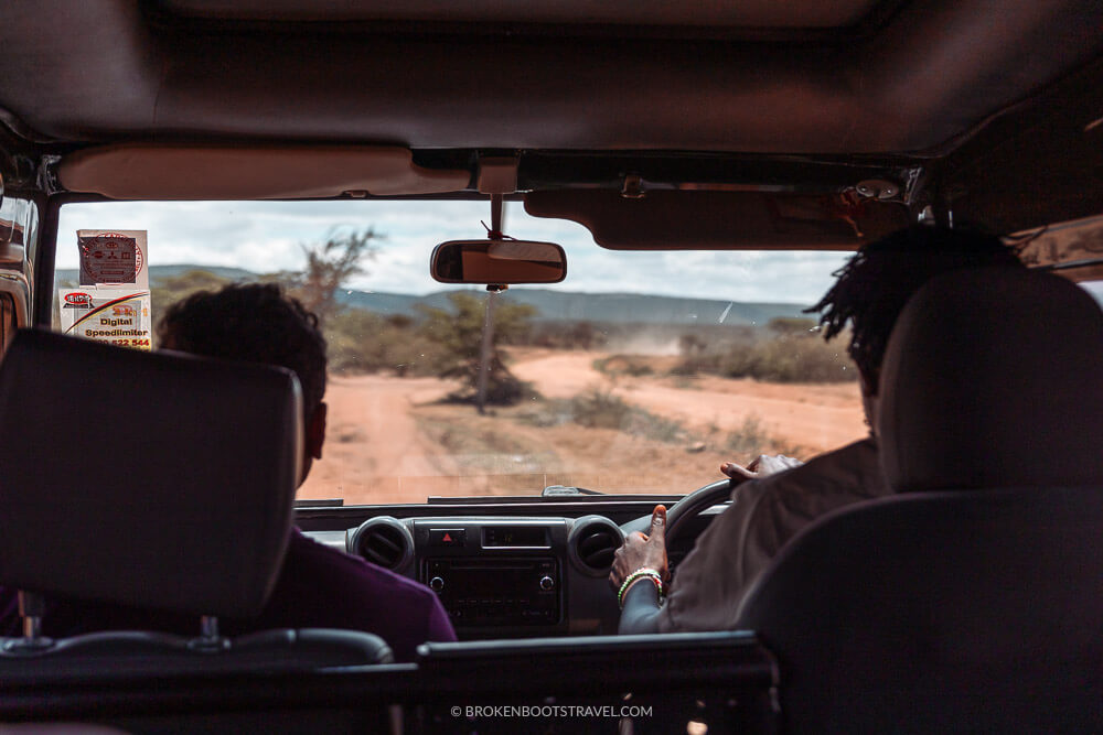 looking out the front window of a car with two men in the foreground