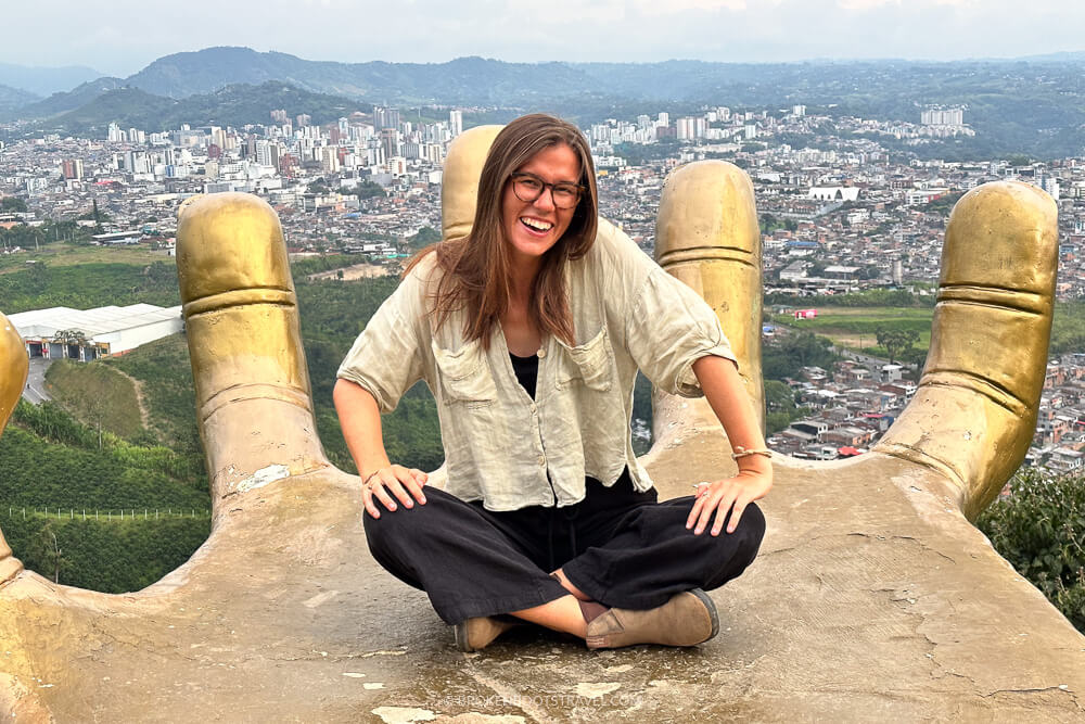 Girl sitting on gold hand with city in background