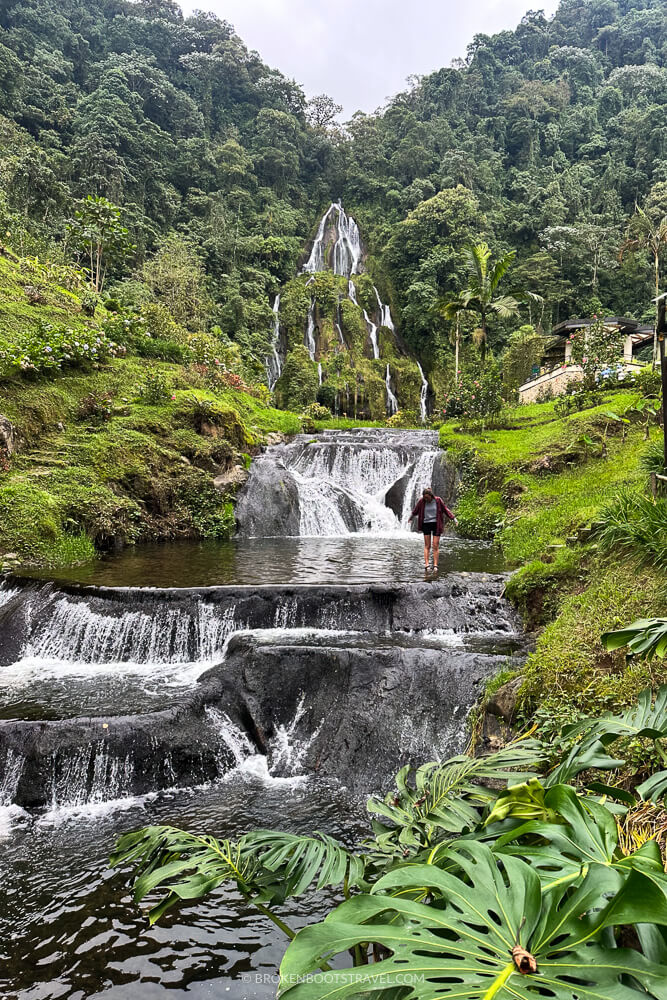 Girl standing in front of waterfall at Termales Santa Rosa de Cabal