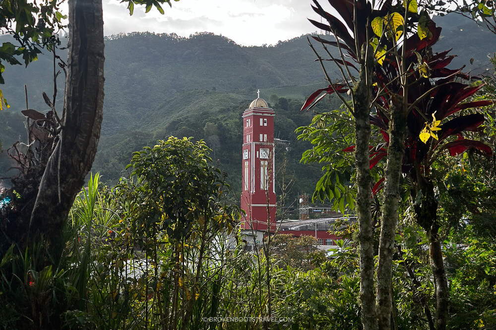 Red church steeple rising above green mountains