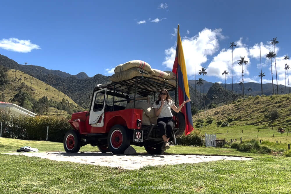 Girl in white shirt sitting on a Jeep Willy with Colombian flag