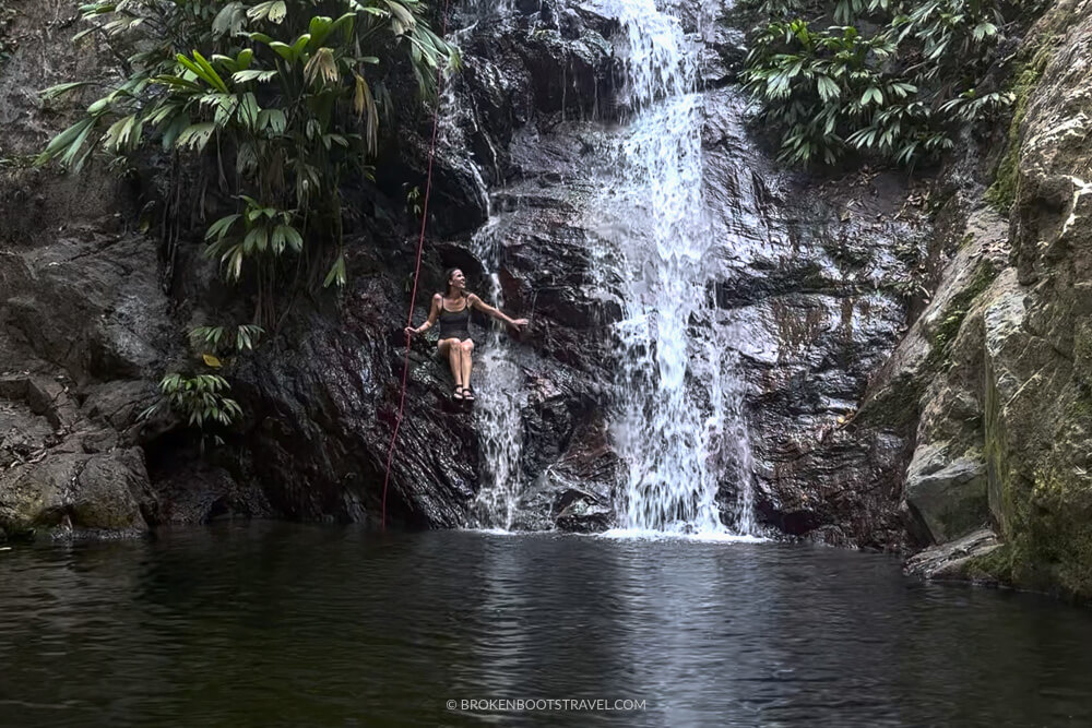 Girl sitting on a waterfall with green plants