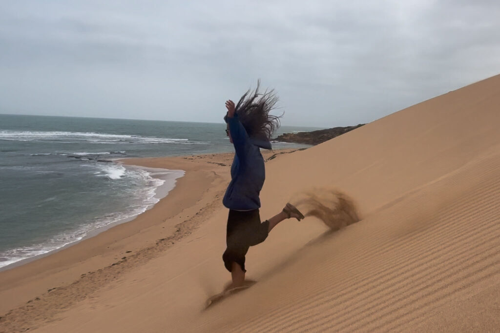 Girl running down a sand dune in La Guajira Colombia