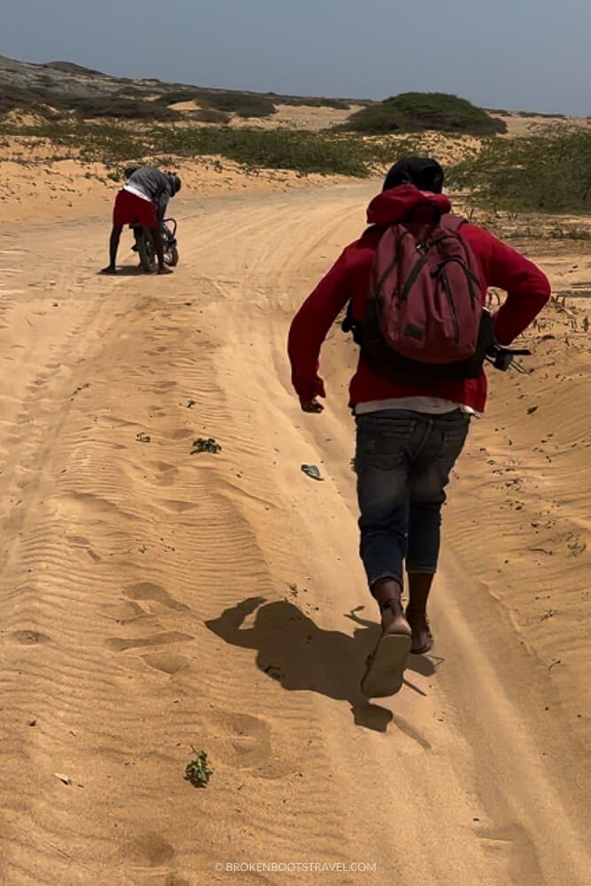 Two men on a desert road with motorcycle