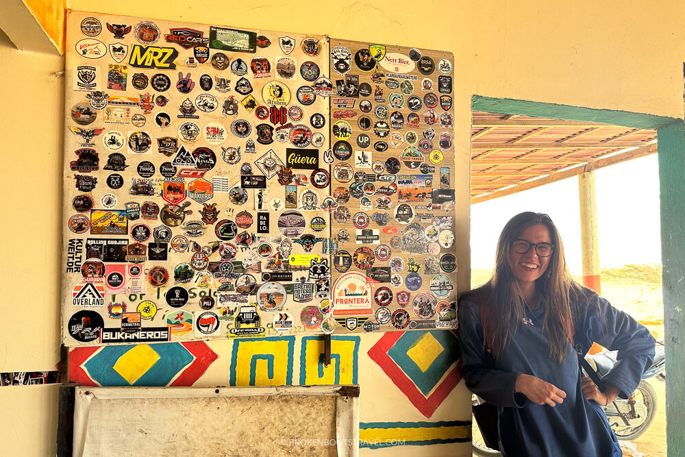 Girl in blue sweatshirt standing by stickers of bikers in La Guajira