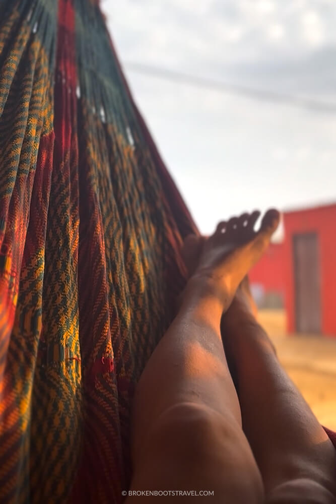 Feet in a colorful hammock with red building