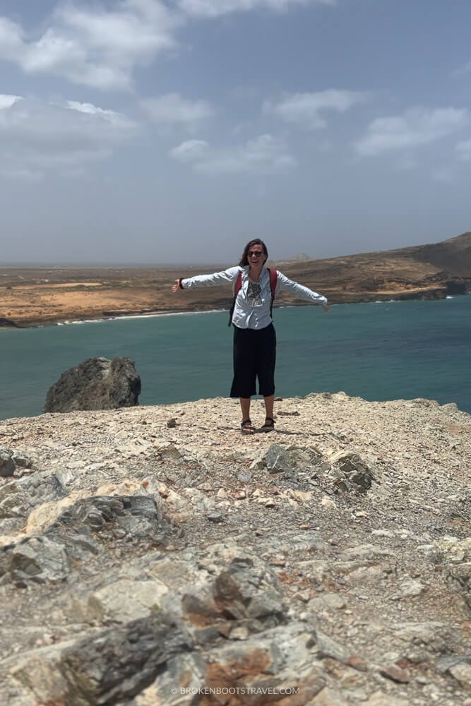 Girl smiling in front of blue ocean and cliffs