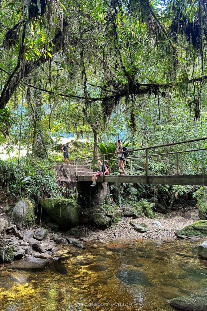 Two people smiling on a bridge over a river Lost city Trek Colombia