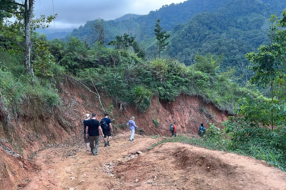 People hiking down a trail with large mountains in the background