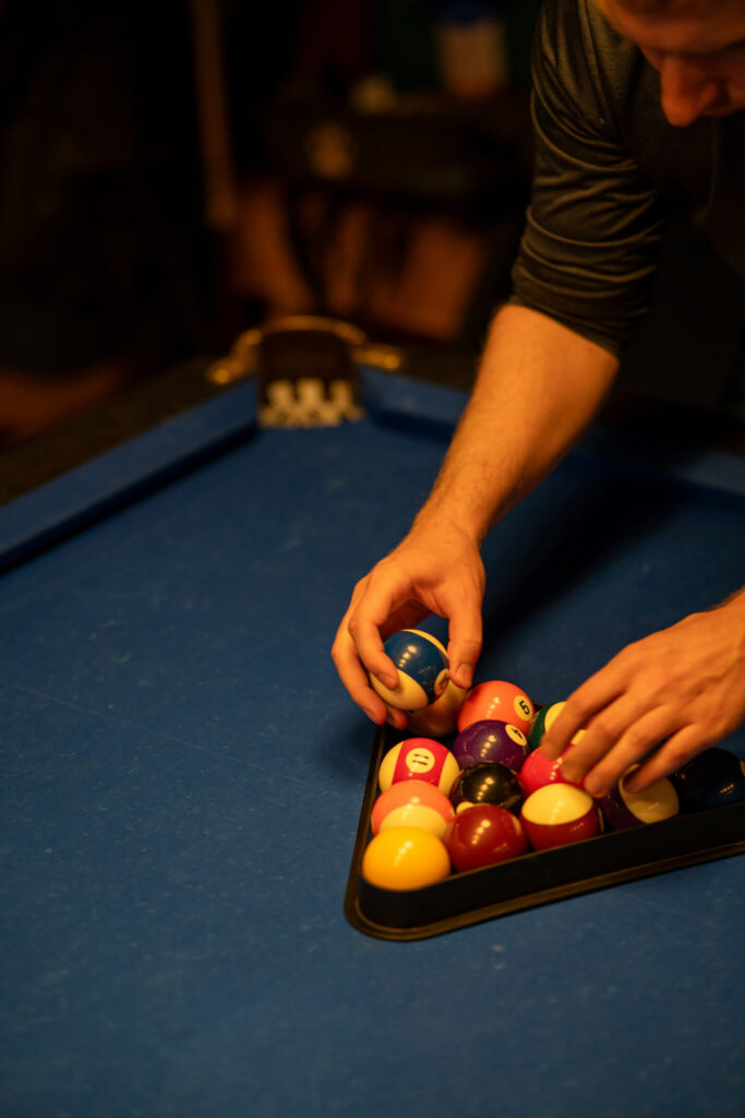 Hands arranging pool balls in a triangle