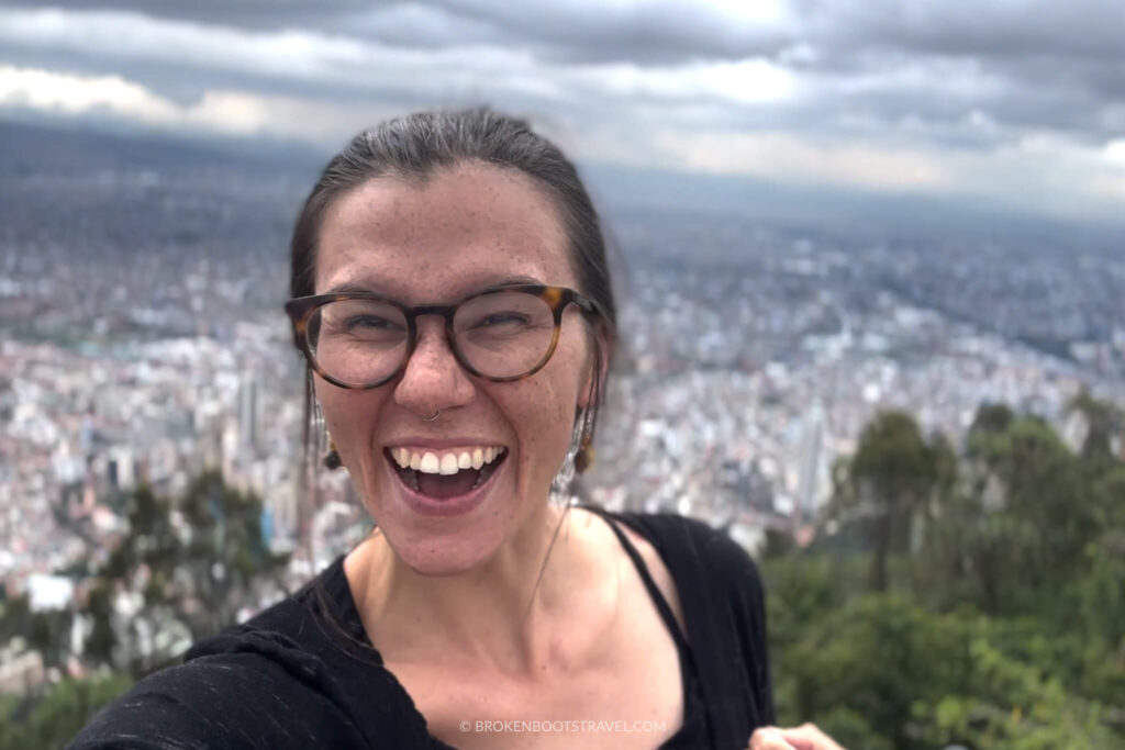 Girl in black shirt and glasses smiling with skyline of Bogota, Colombia in the background