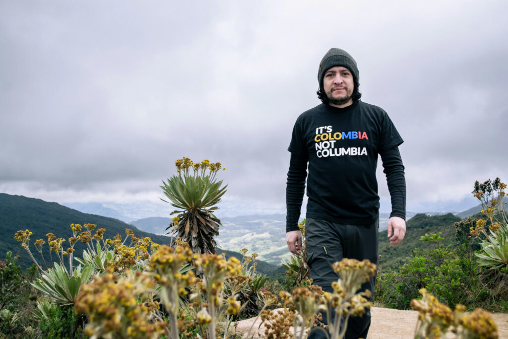 Man on a mountain wearing shirt that reads "It's Colombia, not Columbia"