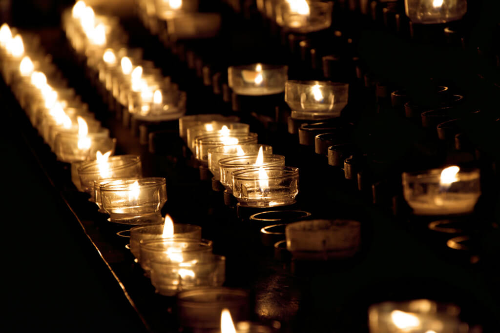 small tea candles lined up along a black background