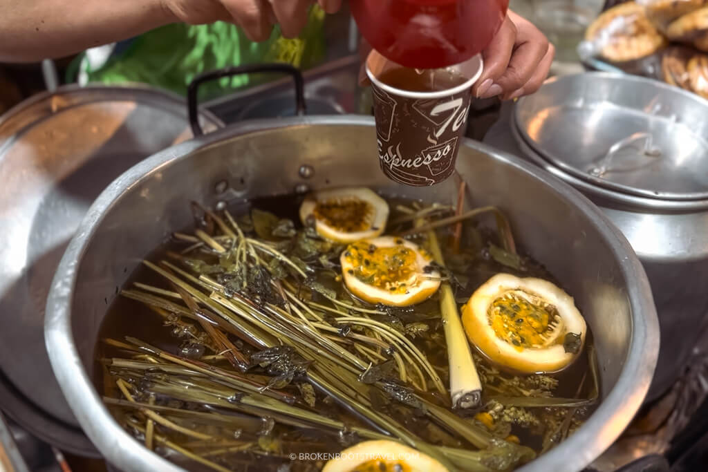 hands pouring canelazo into a glass and drink withj fruit in it