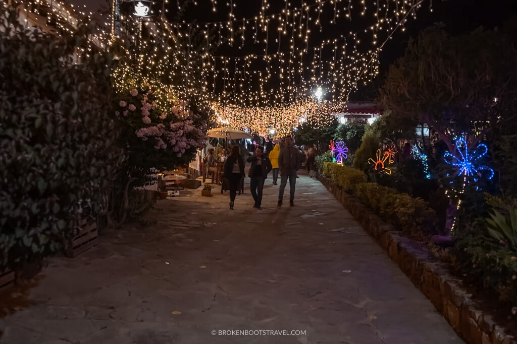 people walking on the street underneath christmas lights