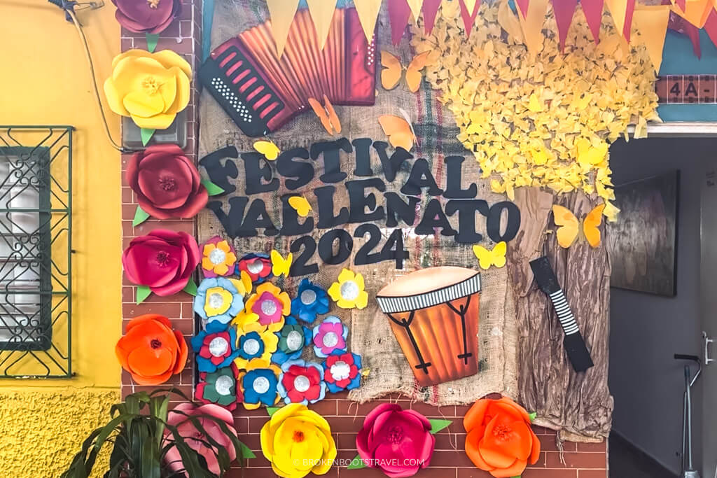 Sign reading "Festival Vallenato 2024" with paper cutouts and flowers