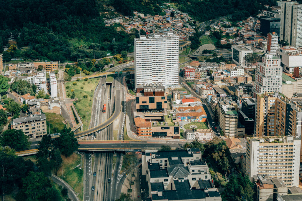 Birds eye view over the city of bogota, colombia with a red bus on the highway below, bogota medellin itinerary