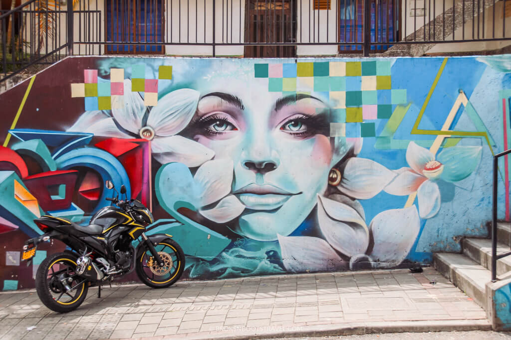 Mural of a woman on a wall in Comuna 13, Medellin with motorcycle in the front