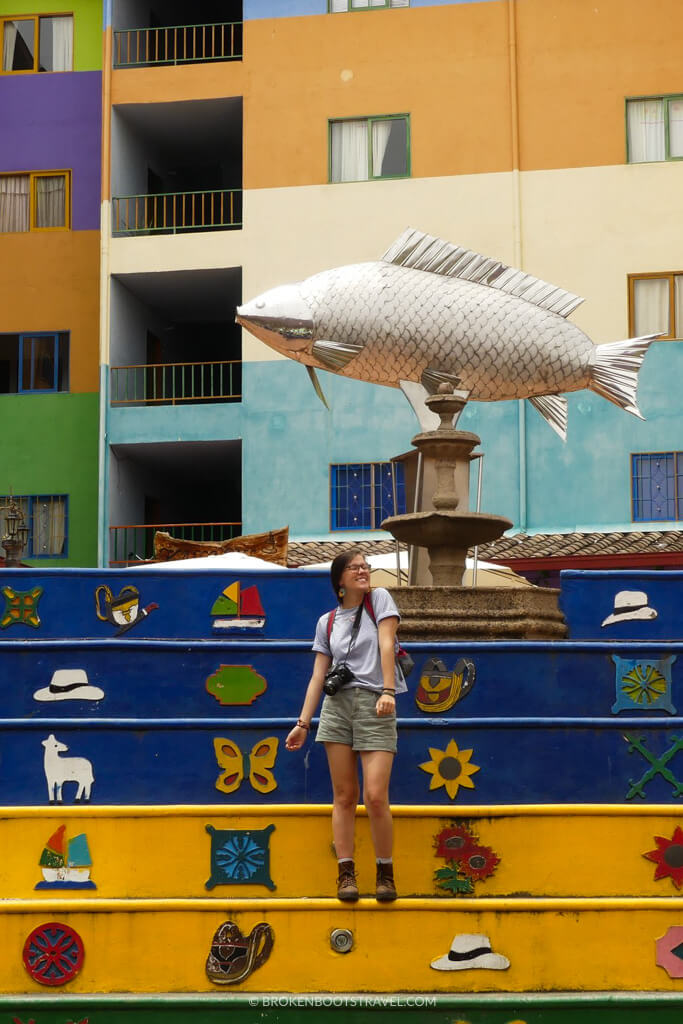 Girl in blue shirt smiling in front of coorful steps and statue of fish