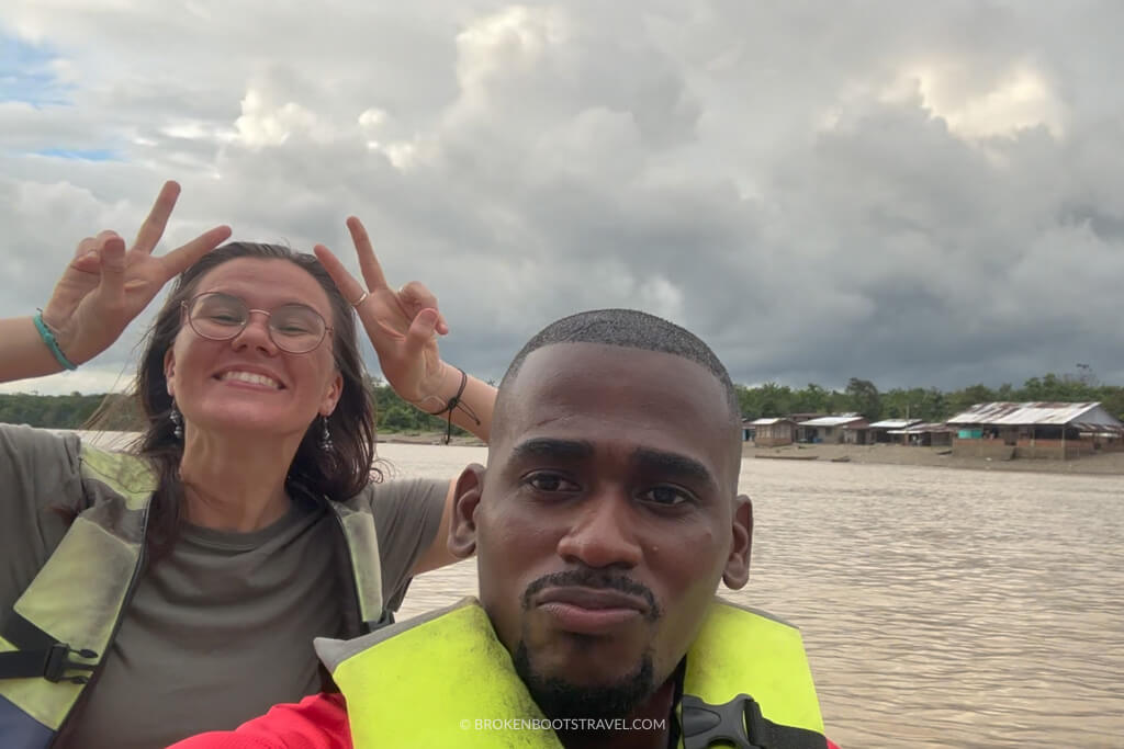 two people posing in a boat on a river wearing lifejackets