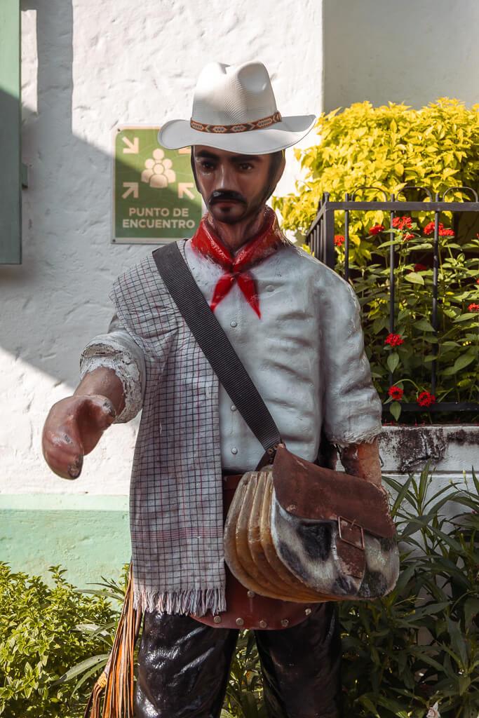 Statue of a paisa man carrying a carriel satchel and wearing an aguadeño hat