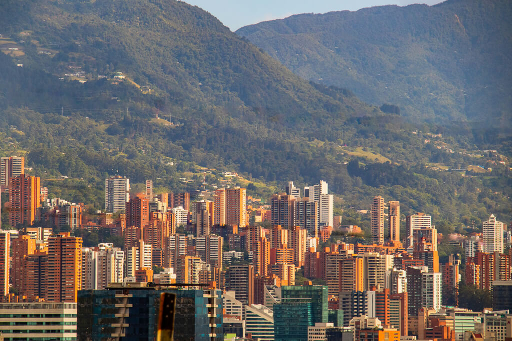 View of skyscrapers with tall green mountains in the background