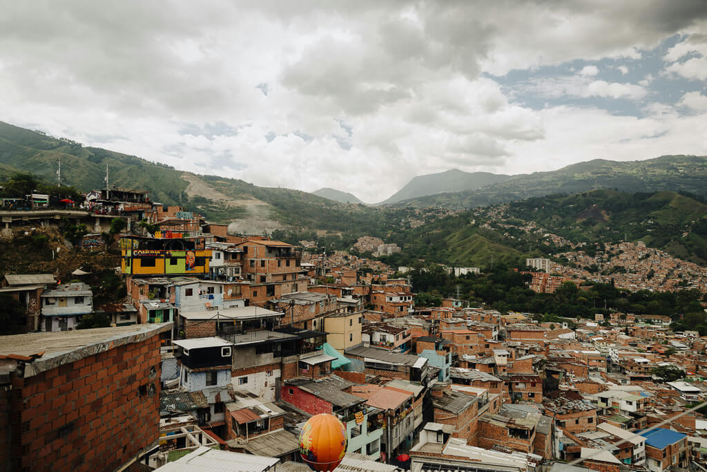 Looking out over the brick buildings of La Comuna 13 in Medellin with clouds and green mountains