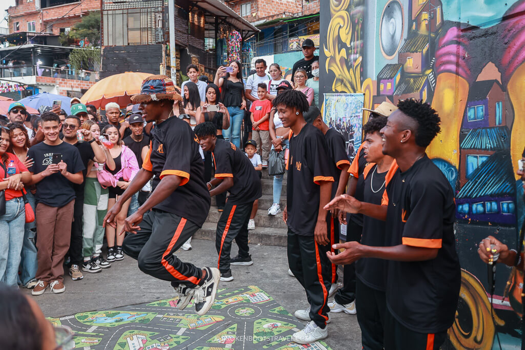 Street dancers in black and orange outfits on a colorful street in La Comuna 13, Medellin, Colombia