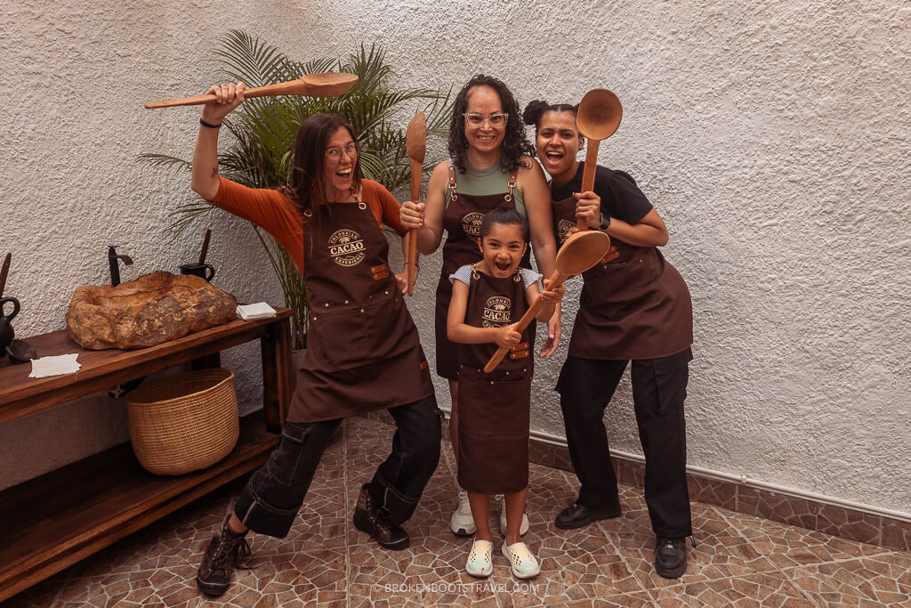 Four women wearing aprons reading "Colombian Cacao Experience" holding big spoons