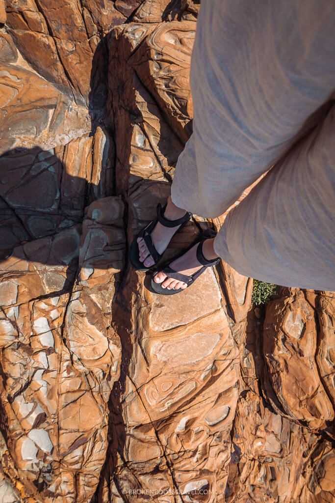 Feet in black sandals on brown rocks