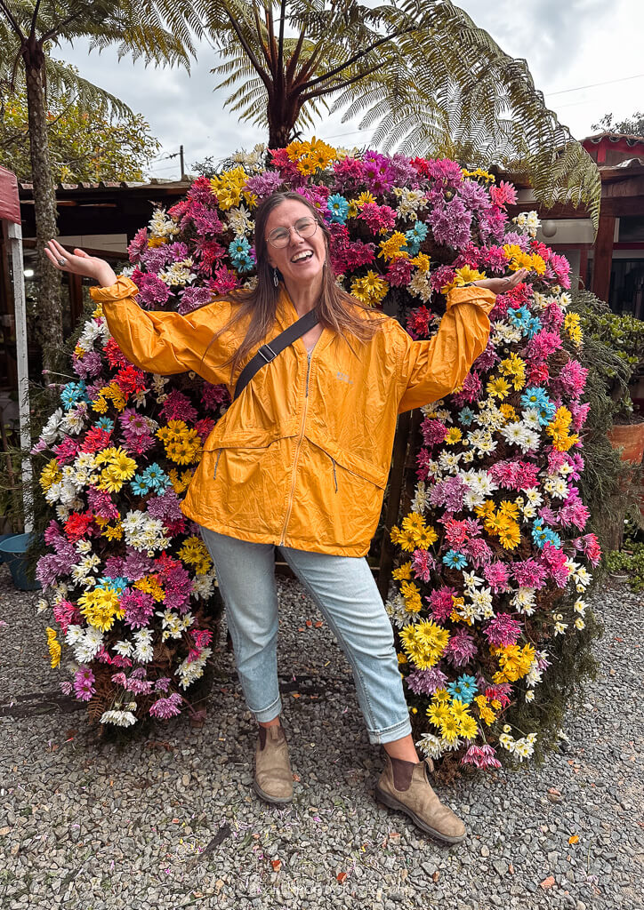 Girl in yellow rainjacket in front of a wall of flowers