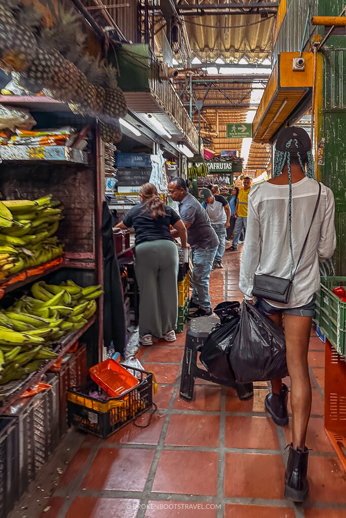 Man wearing a white shirt wandering through a colorful fruit market
