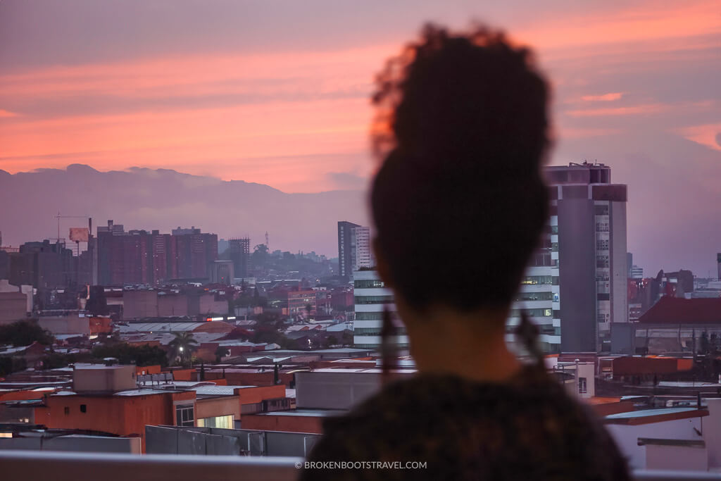 Silhouette of a woman overlooking sunrise over Medellin skyline