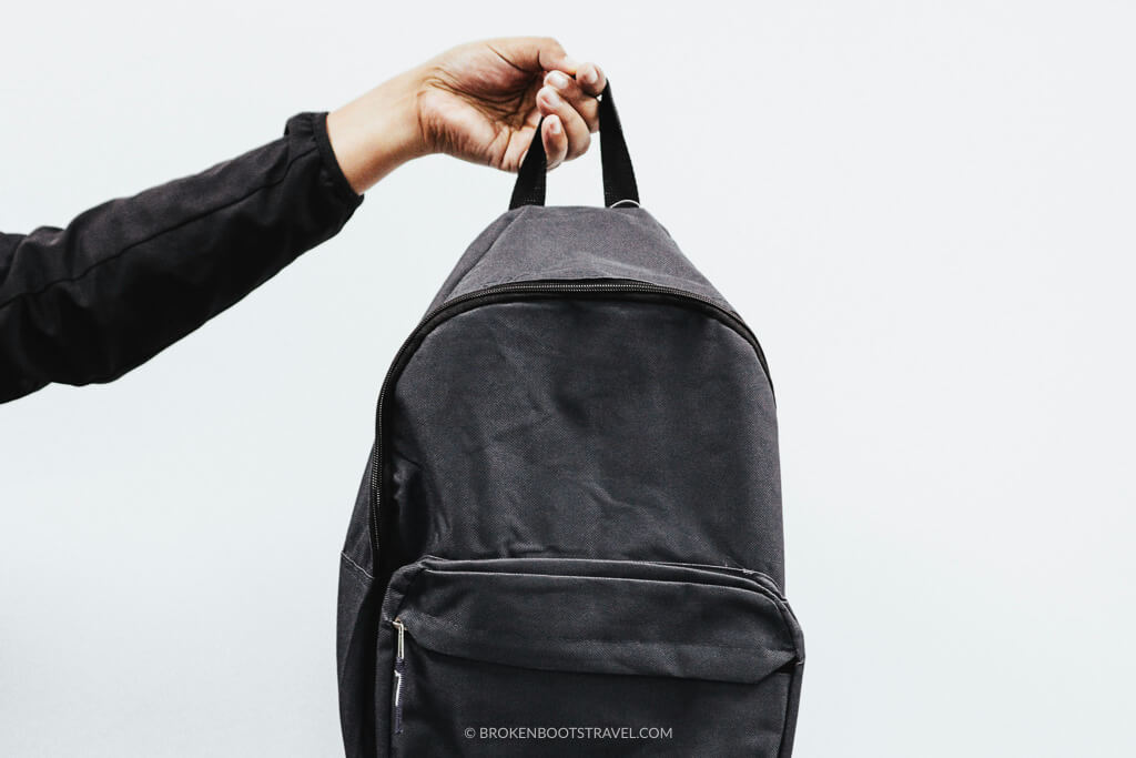 Hand holding up a black backpack