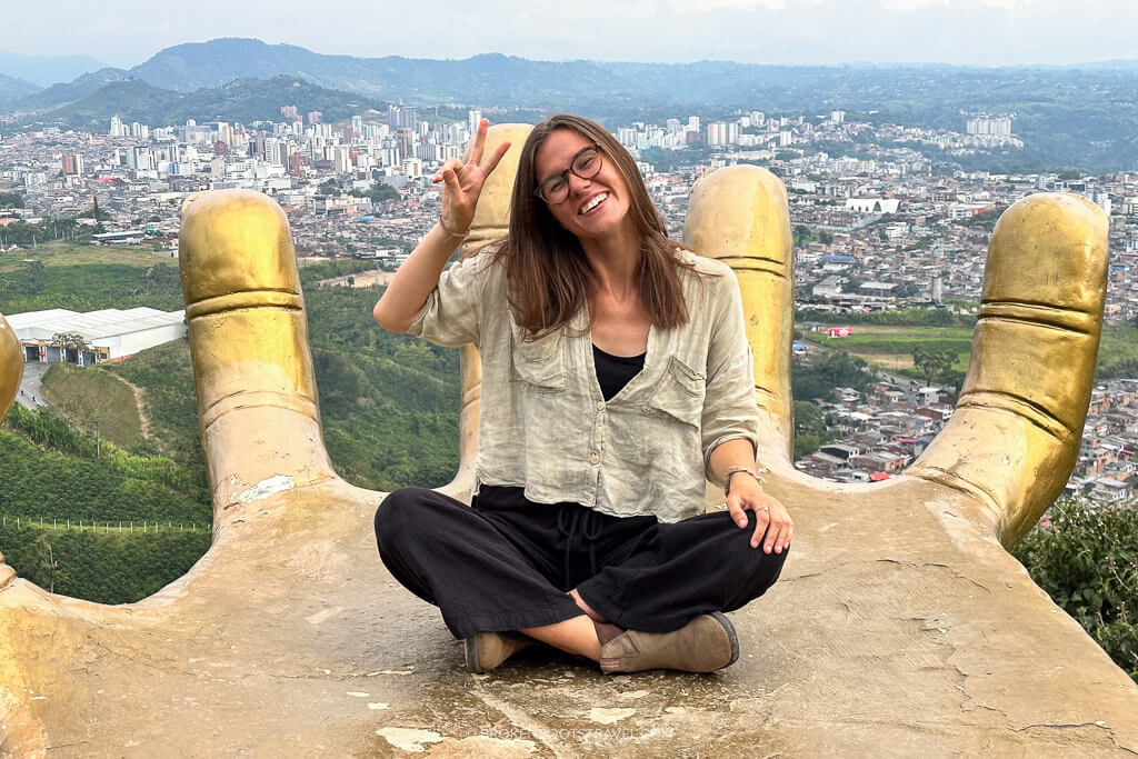 Girl smiling and doing a peace sign in front of a city skyline in Colombia