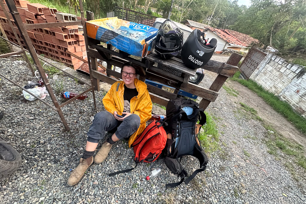 Girl in yellow rainjacket sitting beside backs on the ground