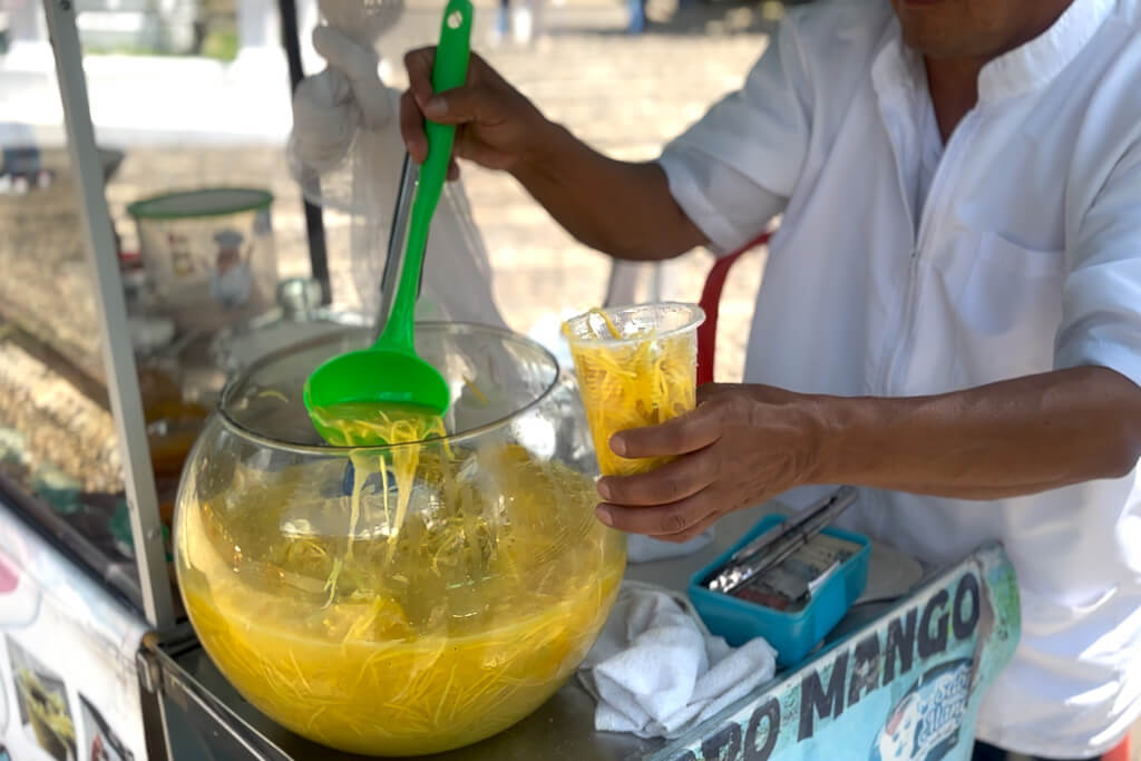 Hands serving fresh Mango Biche from a bowl