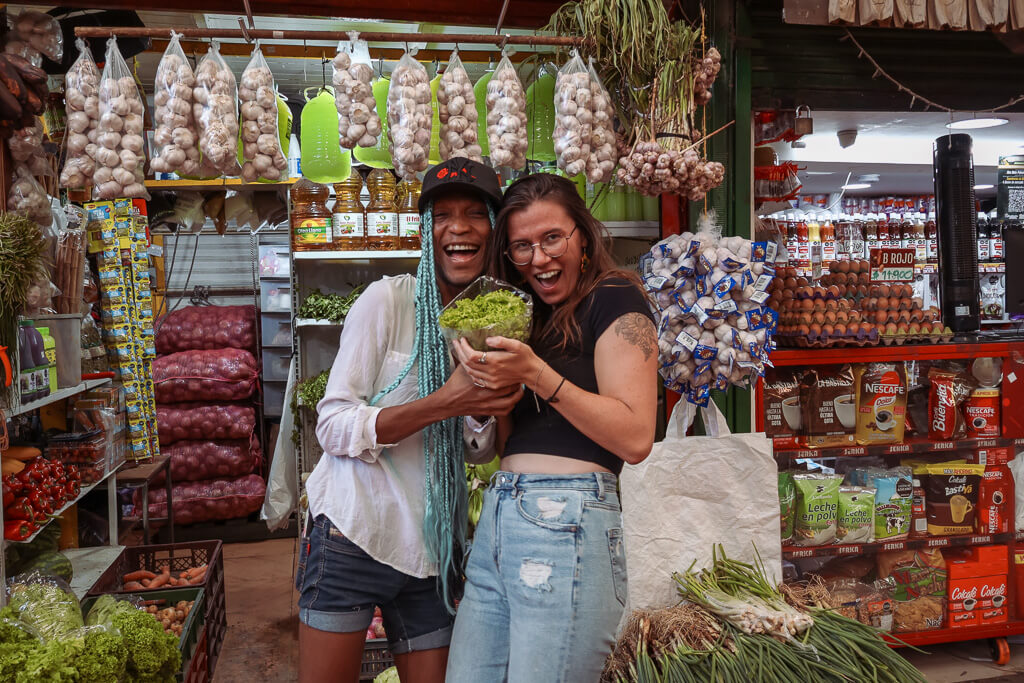 Two people smiling and holding lettuce in a fruit market