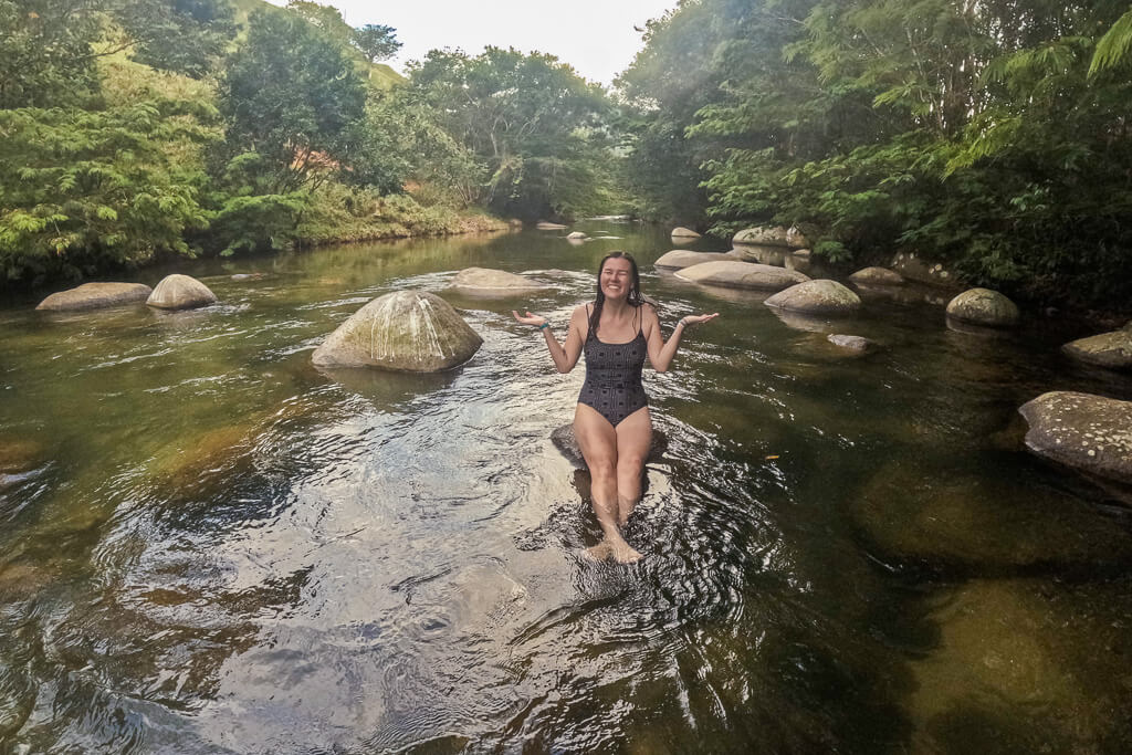 Girl in brown bathing suit posing on a rock in a river