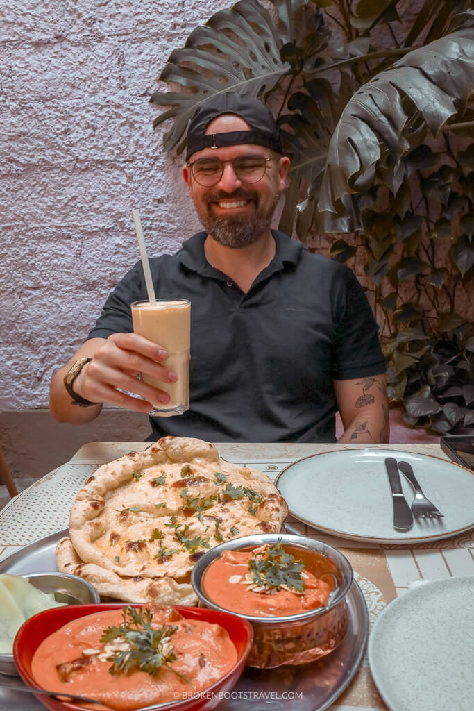 Man in black baseball cap smiling with Indian food
