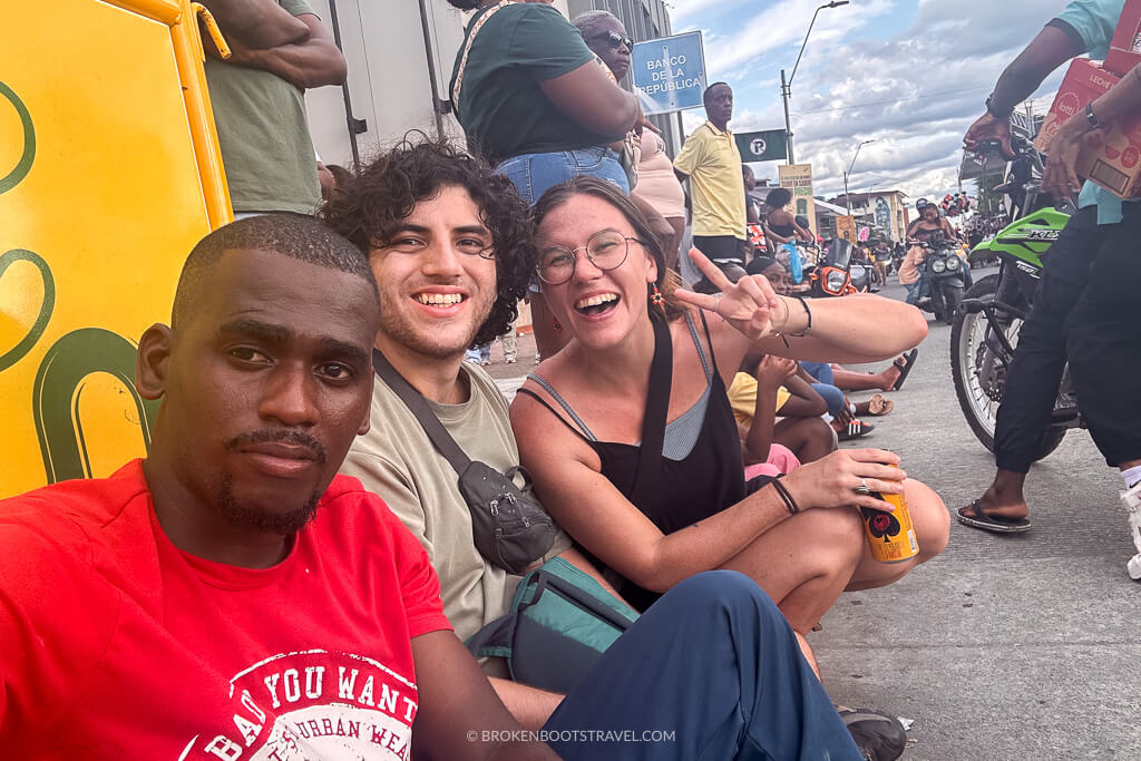 Three people smiling at the camera in front of a parade at the San Pacho Festival