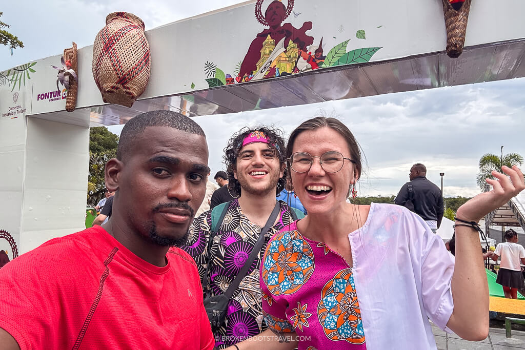Three people taking a selfie in front of the sign for the San Pacho Festival in Quibdó, Colombia