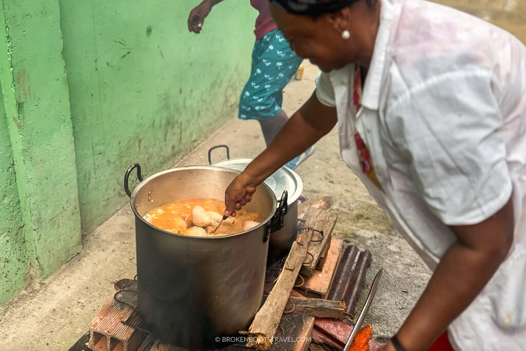 A woman stirring a pot of sancocho in the street