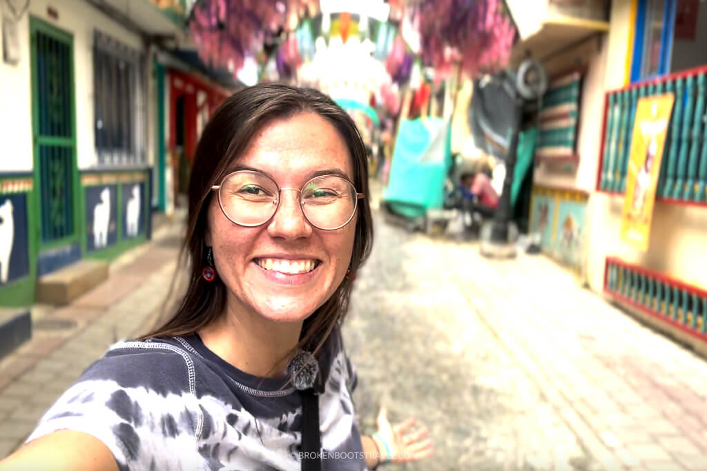 Girl smiling in front of a colorful street in Guatapé, Colombia