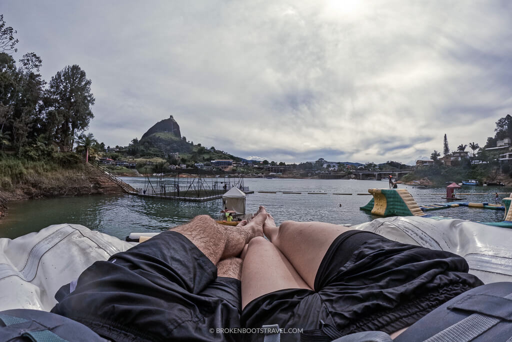 Two people's feet on top of an inflatable with views of Guatapé's Peñol