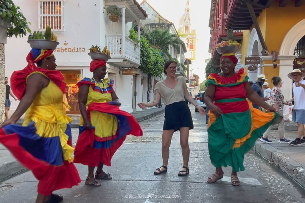 Girl in yellow shirt dancing with palenqueras in Cartagena, Colombia